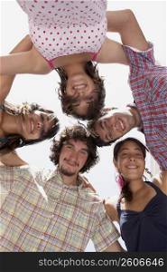 Low angle view of three young women and two young men in a huddle