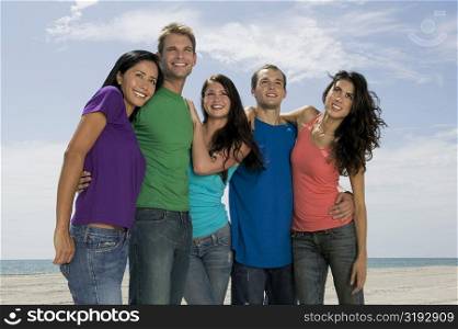Low angle view of three young women and two young men jumping on the beach