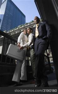 Low angle view of two businessmen and a businesswoman standing together