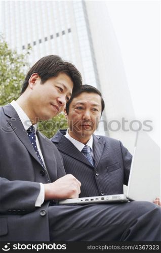 Low angle view of two businessmen using a laptop