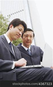 Low angle view of two businessmen using a laptop