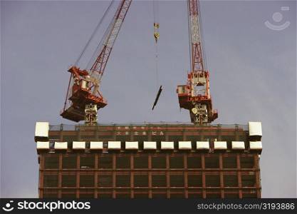 Low angle view of two cranes at a construction site, Tokyo Prefecture, Japan