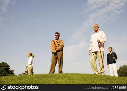 Low angle view of two men and two women standing at a golf course