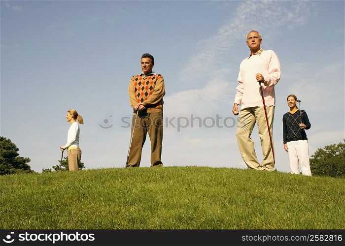 Low angle view of two men and two women standing at a golf course
