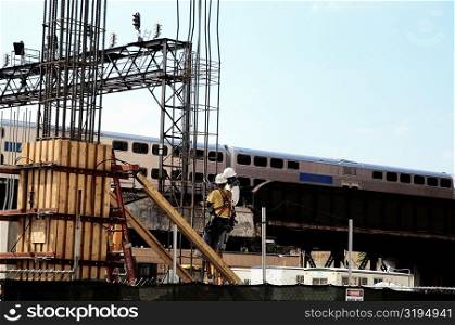 Low angle view of two men working on a platform near the railroad tracks