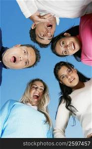 Low angle view of two mid adult men and a mid adult woman with two young women in a huddle