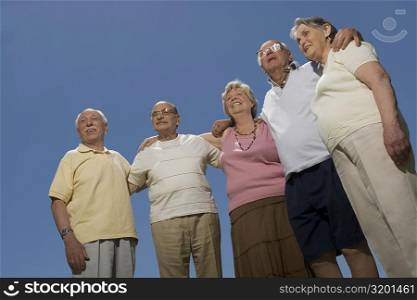 Low angle view of two senior women and three senior men standing together with arm around