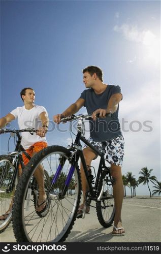 Low angle view of two young men on bicycles
