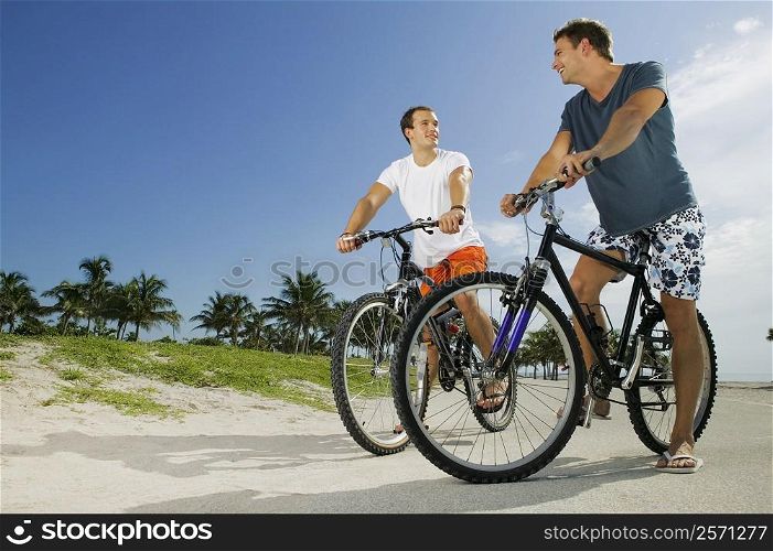 Low angle view of two young men on bicycles