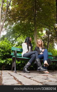 Low angle view of two young relaxed female friends chatting in the park