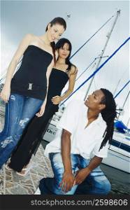 Low angle view of two young women and a young man at a dock