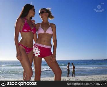Low angle view of two young women standing on the beach