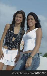 Low angle view of two young women standing together and smiling
