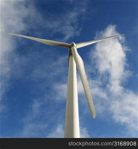 Low angle view of wind turbine against blue sky and clouds.