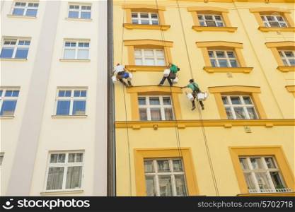 Low angle view of window washers hanging outside building