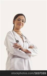 Low angle view of young confident female doctor standing against white background