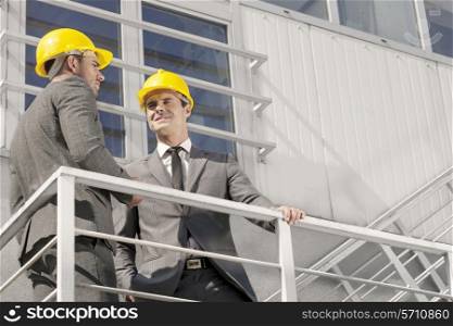 Low angle view of young male architect with coworker discussing on stairway