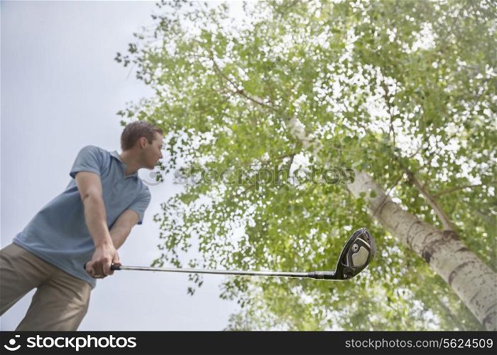 Low angle view of young man getting ready to hit the golf ball on the golf course