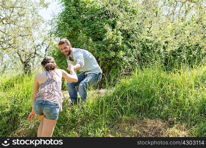 Low angle view of young man helping young woman up hill