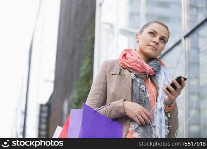 Low angle view of young woman listening to music while shopping