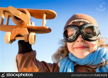 Low angle view portrait of funny kid playing with toy airplane against blue sky background