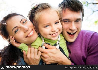 Low angle view portrait of happy smiling family in autumn. Focus on woman