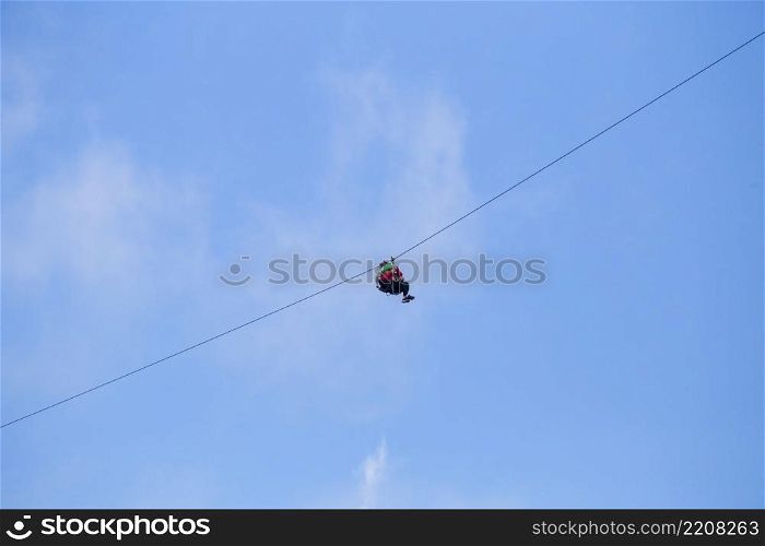 low angle view tourist riding zip line adventure against blue sky