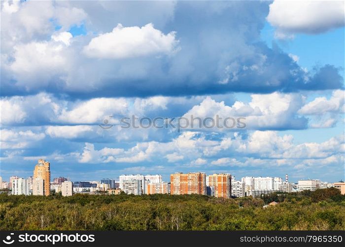 low blue clouds over green forest and city in summer