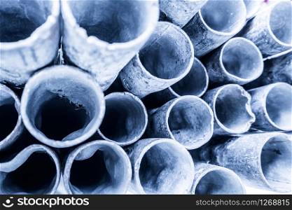 Low depth of field image of metal pipe stack in blue shade tone. Rounded iron pipe shape.