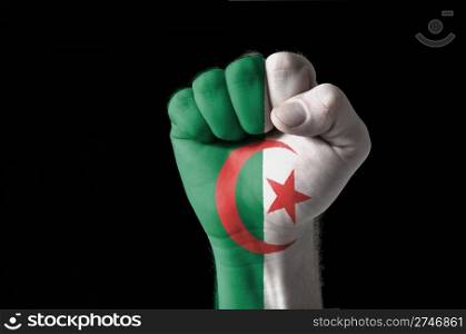Low key picture of a fist painted in colors of algeria flag