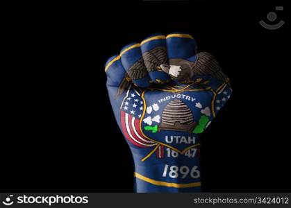 Low key picture of a fist painted in colors of american state flag of utah