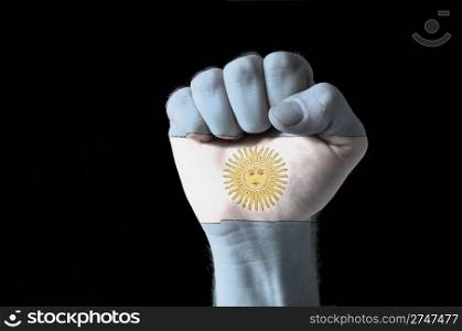 Low key picture of a fist painted in colors of argentina flag