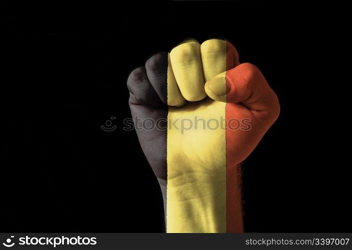 Low key picture of a fist painted in colors of belgium flag