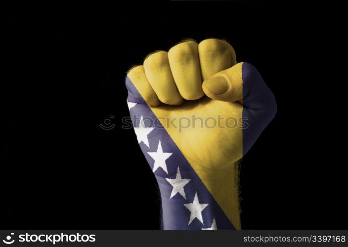 Low key picture of a fist painted in colors of bosnia and herzegovina flag