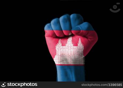 Low key picture of a fist painted in colors of cambodia flag