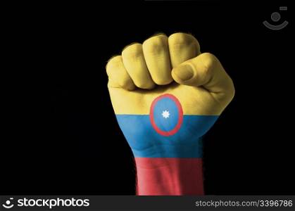 Low key picture of a fist painted in colors of columbia flag
