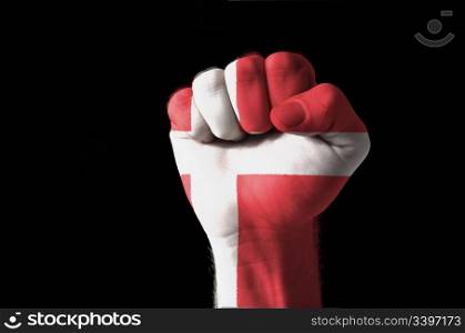 Low key picture of a fist painted in colors of denmark flag