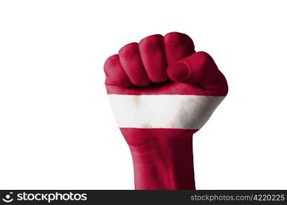 Low key picture of a fist painted in colors of latvia flag