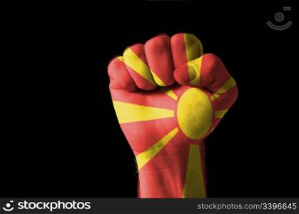 Low key picture of a fist painted in colors of macedonia flag