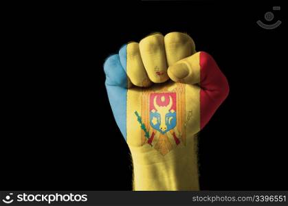Low key picture of a fist painted in colors of moldova flag