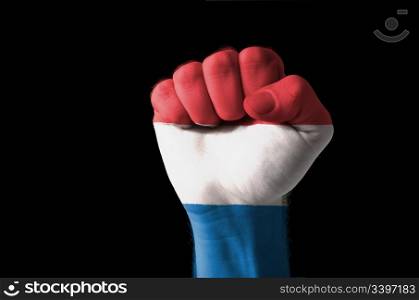 Low key picture of a fist painted in colors of netherlands flag