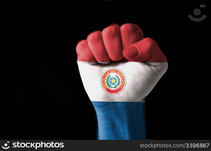 Low key picture of a fist painted in colors of paraguay flag