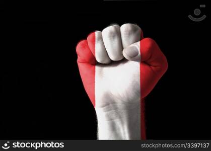 Low key picture of a fist painted in colors of peru flag