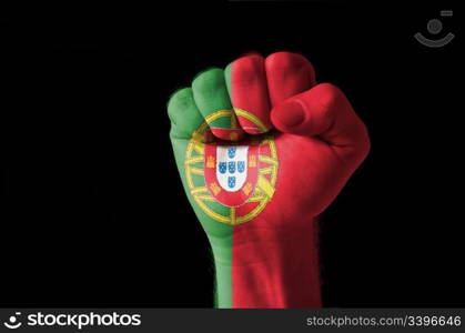 Low key picture of a fist painted in colors of portugal flag