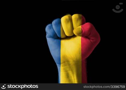 Low key picture of a fist painted in colors of romania flag