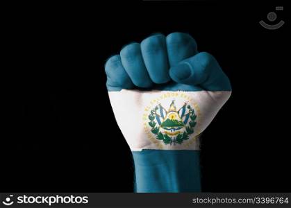Low key picture of a fist painted in colors of san salvador flag
