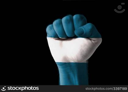 Low key picture of a fist painted in colors of san salvador flag