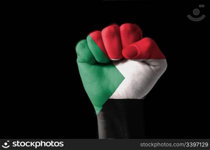 Low key picture of a fist painted in colors of sudan flag