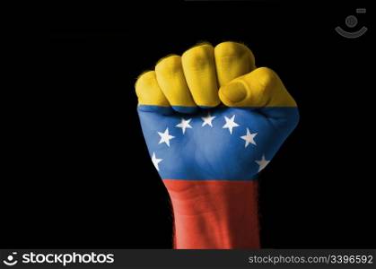 Low key picture of a fist painted in colors of venezuela flag