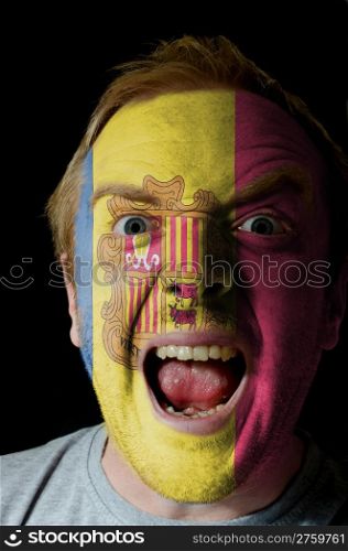 Low key portrait of an angry man whose face is painted in colors of andoran flag